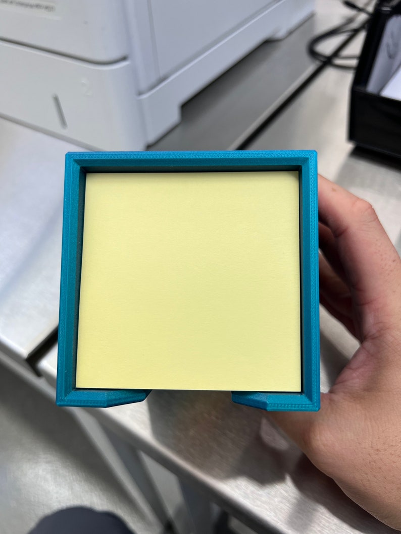 May include: A teal blue plastic desk organizer with a yellow sticky note dispenser.