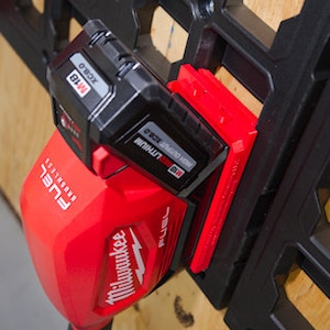 May include: A red and black Milwaukee FUEL power tool with a red and black battery attached. The tool is mounted on a black and gray wall organizer.