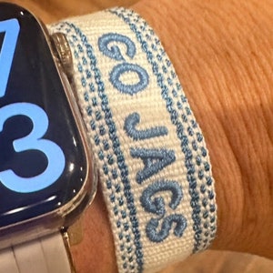 May include: White and blue woven wristband with the text "GO JAGS" in blue embroidery.