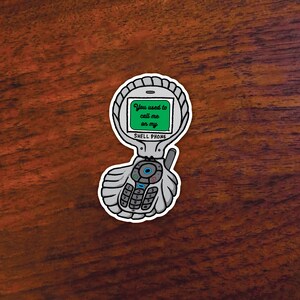 May include: A sticker of a retro shell phone with the text "You used to call me on my" on a green screen. The phone is gray with a white outline and a seashell design. The words "SHELL PHONE" are below the screen.