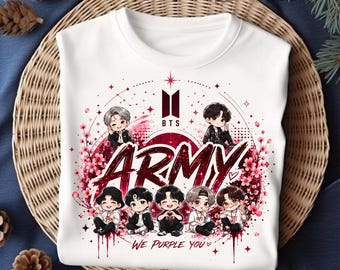 May include: A white t-shirt featuring a graphic print of seven chibi-style characters. The design includes the BTS logo, the word ARMY in large red script, and the text WE PURPLE YOU, surrounded by pink cherry blossom illustrations and stars.