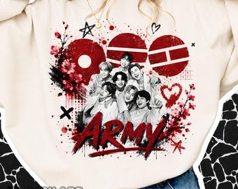 May include: A cream-colored crewneck sweatshirt featuring a graphic print of seven individuals in black and white. The design includes red circular and rectangular shapes, cherry blossom branches, stars, a heart, and the word ARMY in red text.