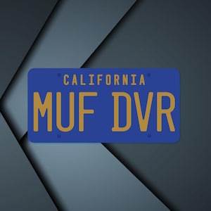 May include: A blue California license plate with gold lettering that reads "MUF DVR." The word "CALIFORNIA" is above the letters. The background is a dark, geometric design.