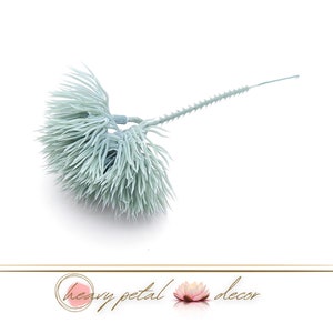 Könnte beinhalten: Ein einzelner, hellblauer, künstlicher Blumenstiel mit einem flauschigen, bürstenartigen Kopf. Der Stiel ist lang und dünn, mit einem Drahtkern.