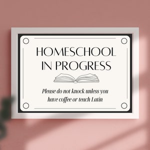 Può includere: Un cartello bianco e nero con il testo "HOMESCHOOL IN PROGRESS" e un'illustrazione di un libro aperto. Il cartello dice anche "Si prega di non bussare a meno che non si abbia caffè o si insegni latino."