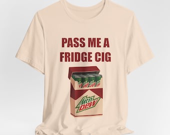 Puede incluir: Camiseta beige con el texto "PASS ME A FRIDGE CIG" en granate. La camiseta presenta un gráfico de una caja de cigarrillos con latas de Mountain Dew en su interior. La caja es roja y blanca con el logotipo de Mountain Dew.