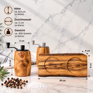 K&ouml;nnte beinhalten: Zwei zylindrische Pfefferm&uuml;hlen aus Olivenholz mit schwarzen Metallkurbeln und ein passender rechteckiger Holzsockel mit zwei kreisf&ouml;rmigen Vertiefungen. Die M&uuml;hlen sind 8,3 cm hoch, haben 5 cm Durchmesser und wiegen 400 Gramm. Der Sockel misst 20 cm mal 8 cm mal 6 cm.