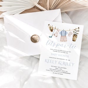 Może przedstawiać: Zaproszenie na baby shower z akwarelową ilustracją golfowego stroju dla dziecka wiszącego na sznurku do suszenia. Zaproszenie zawiera napis "Let's Par-Tee" oraz imiona "Keely & Riley" i datę oraz godzinę imprezy.