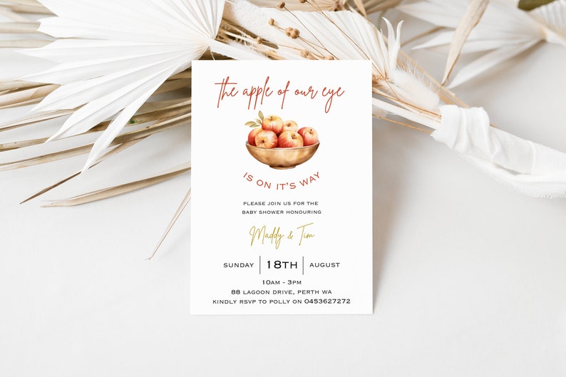 May include: A baby shower invitation with a watercolor illustration of red apples in a bowl. The text reads "the apple of our eye is on it's way". The invitation is for Madly & Tim on Sunday, August 18th from 10am to 3pm at 88 Lagoon Drive, Perth WA. RSVP to Polly at 0453627272.