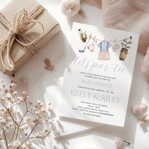 Może przedstawiać: Zaproszenie na baby shower z akwarelową ilustracją golfowego stroju dla dziecka wiszącego na sznurku. Zaproszenie zawiera napis "lets par-tee" oraz datę, godzinę i miejsce wydarzenia.