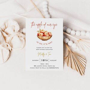 May include: A baby shower invitation with a watercolor illustration of a bowl of red apples. The text reads "The apple of our eye is on it's way." The invitation is for a baby shower honoring Maddy & Tim on Sunday, August 18th from 10am to 3pm at 88 Lagoon Drive, Perth WA. RSVP to Polly at 0453627272.