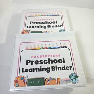 May include: Two white three-ring binders featuring a cover insert titled Pacesetters Preschool Learning Binder. The design includes a row of colorful pencils, a paint palette, a chalkboard with ABC text, a backpack, books, and a globe illustration.