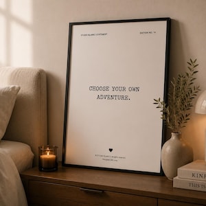 Könnte beinhalten: Ein vertikales, rechteckiges Wandbild in einem dünnen schwarzen Rahmen mit weißem Hintergrund und schwarzem Text, der mittig "CHOOSE YOUR OWN ADVENTURE." lautet, oben links "STUDIO BLANKO STATEMENT" und oben rechts "EDITION NO. 14".