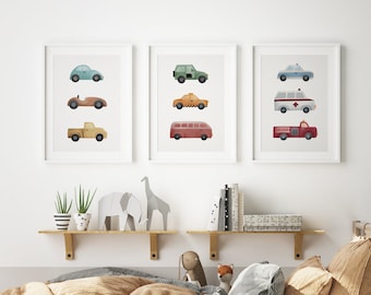 May include: Three framed prints of colorful illustrations of different vehicles, including a police car, ambulance, fire truck, bus, taxi, race car, pickup truck, and a jeep. The prints are hanging on a white wall above a wooden bed with a tan duvet and pillows.