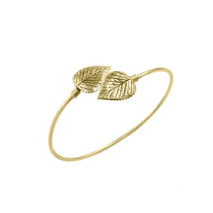 May include: A gold bangle bracelet with two leaf-shaped charms.