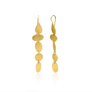Könnte beinhalten: Ein Paar lange, goldfarbene Ohrringe. Jeder Ohrring hat eine Reihe von verbundenen, strukturierten, ovalen und tropfenförmigen Elementen. Die Ohrringe hängen an einem einfachen Haken, wodurch ein hängender Effekt entsteht. Auf weißem Hintergrund.