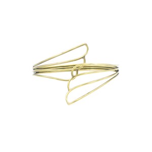May include: A gold-toned metal bracelet with a unique, abstract design. The bracelet is made of multiple thin wires that are intertwined to create a geometric pattern.
