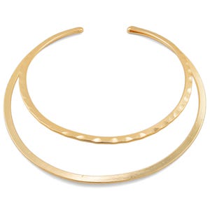 May include: A gold-toned double-layered choker necklace. The top layer is a hammered, textured band, while the bottom layer is a smooth, polished band.