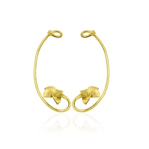 May include: A pair of gold ear cuffs with a floral design. The cuffs are made of a thin, curved wire with a small flower at the end of each wire.