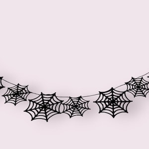 May include: A black spiderweb garland, ideal for Halloween decorations. The garland features multiple spiderwebs connected by a thin string, creating a festive and spooky atmosphere. The webs are detailed and symmetrical.