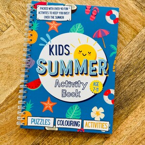 May include: A blue and yellow activity book for kids with a summer theme. The cover features a sun, a watermelon, a pineapple, a starfish, a palm leaf, and a flower. The title is "Kids Summer Activity Book" and the age range is 7-11. The book includes puzzles, coloring, and activities.
