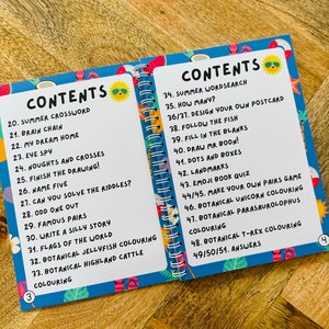 May include: A blue and white book with a colorful cover featuring a smiling sun wearing sunglasses. The book is titled "Contents" and lists activities for kids, including summer crossword, brain chain, eye spy, and more.