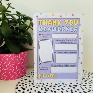 May include: A thank you card for a keyworker, featuring the text "THANK YOU KEYWORKER" in yellow and blue. The card has fill-in sections for the sender to personalize the message. A potted plant is in the background, with a black and white spotted surface.