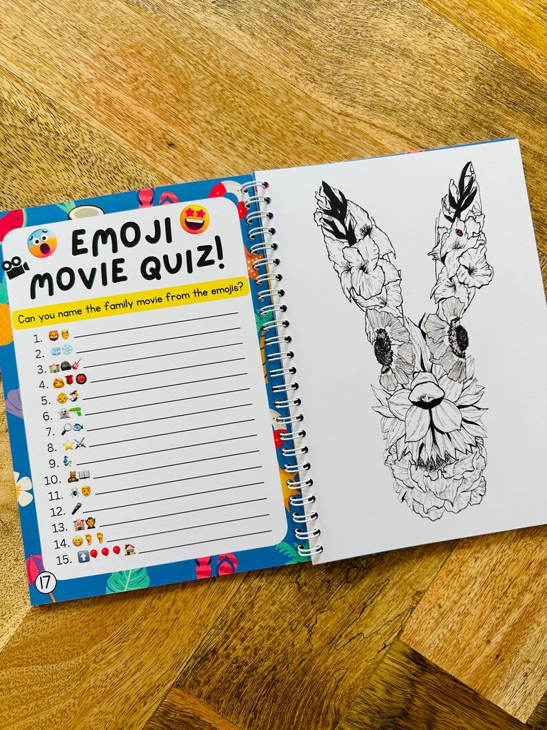 May include: A blue and yellow book with the text "Emoji Movie Quiz!" and a list of numbers with emojis next to them. The book is open to a page with a black and white drawing of a rabbit with flowers on its head.