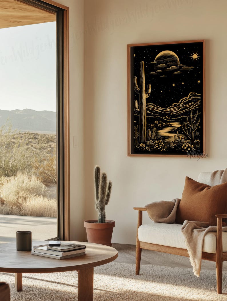 The framed print hanging in a cozy seating area beside a large window overlooking the desert landscape, styled with a warm-toned chair and minimal decor.