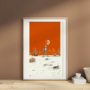 Framed poster resting on a taupe wall shelf with soft ceramic accents and natural lighting, highlighting the desert colors and clean linework.