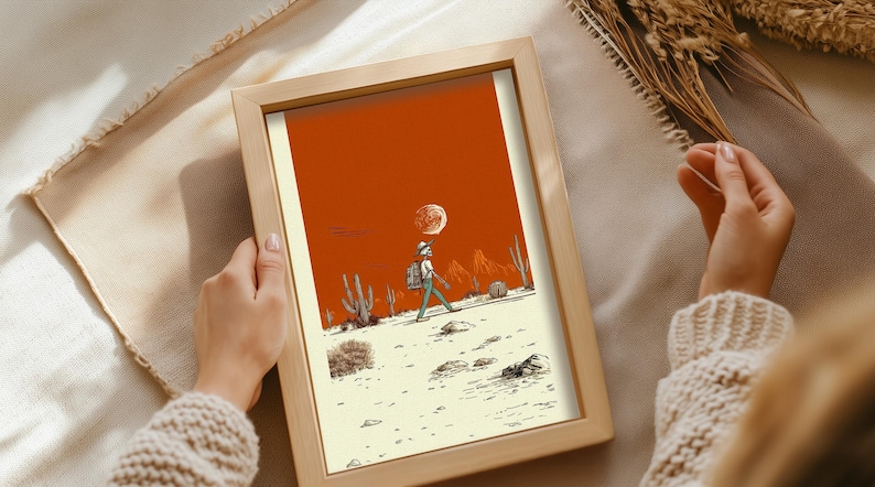 Framed Boho Skeleton Poster featuring a western skeleton figure walking through the desert with bold cactus linework, set against orange mountains and a neutral sky. Being held by a person.