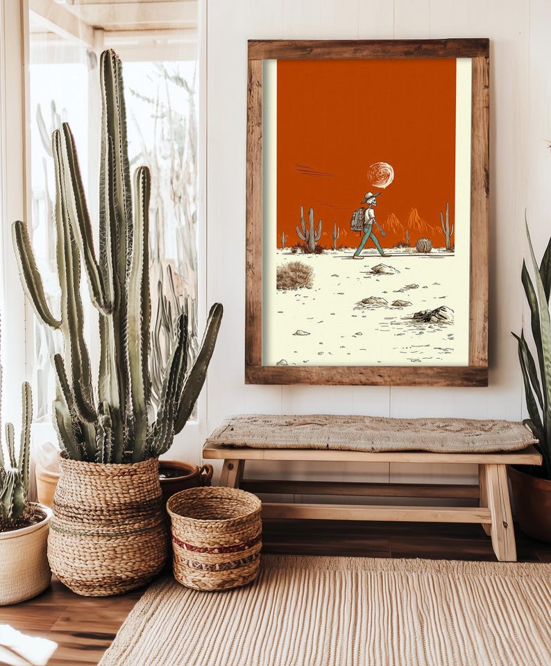 A woman seated cross-legged on a bed holding the framed Boho Skeleton Poster, styled in a warm, earthy bedroom with soft lighting and boho decor.