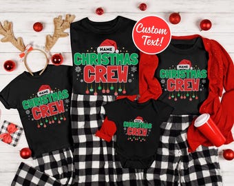 May include: A collection of black Christmas Crew t-shirts and pajamas with a red Santa hat design. The shirts have the text "CHRISTMAS CREW" in green and red. A red cardigan and a baby onesie are also included.