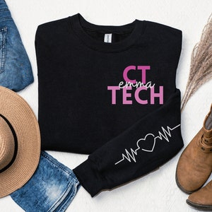 May include: Black sweatshirt with pink text that reads "CT emma TECH" and a white heart beat graphic on the sleeve.