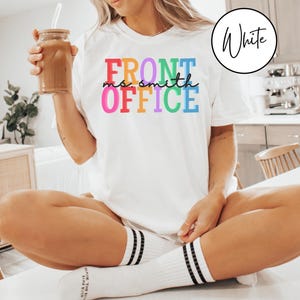 Pu&ograve; includere: Una maglietta bianca con il testo "FRONT OFFICE" in colori arcobaleno. Il testo "ms. smith" &egrave; scritto in nero sotto la parola "FRONT".