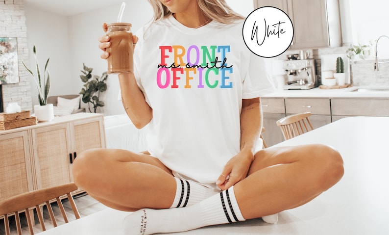 Pu&ograve; includere: Una maglietta bianca con il testo "FRONT OFFICE" in colori arcobaleno. Il testo "ms. smith" &egrave; scritto in nero sotto la parola "FRONT".