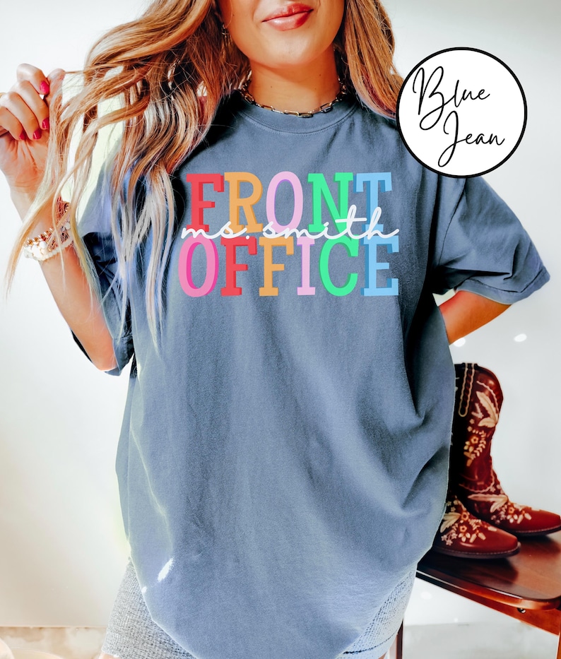 Pu&ograve; includere: Una t-shirt blu jeans con il testo "FRONT OFFICE" in colori arcobaleno. Il testo "no smith" &egrave; scritto in bianco corsivo sopra la parola "OFFICE".