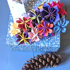 Origami flower ornamental display. Handmade origami flower arrangement set into a beautiful natural giant pinecone base.