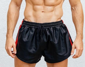 May include: Black shorts with red side stripes and a drawstring waist. The shorts are made of a shiny material. The model is standing in front of a white wall.