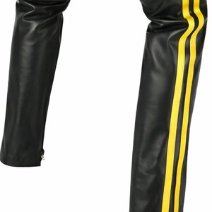 May include: Black leather pants with three vertical yellow stripes down the side of one leg. The pants have a straight leg cut and a zipper at the ankle. The material appears to be smooth and shiny.