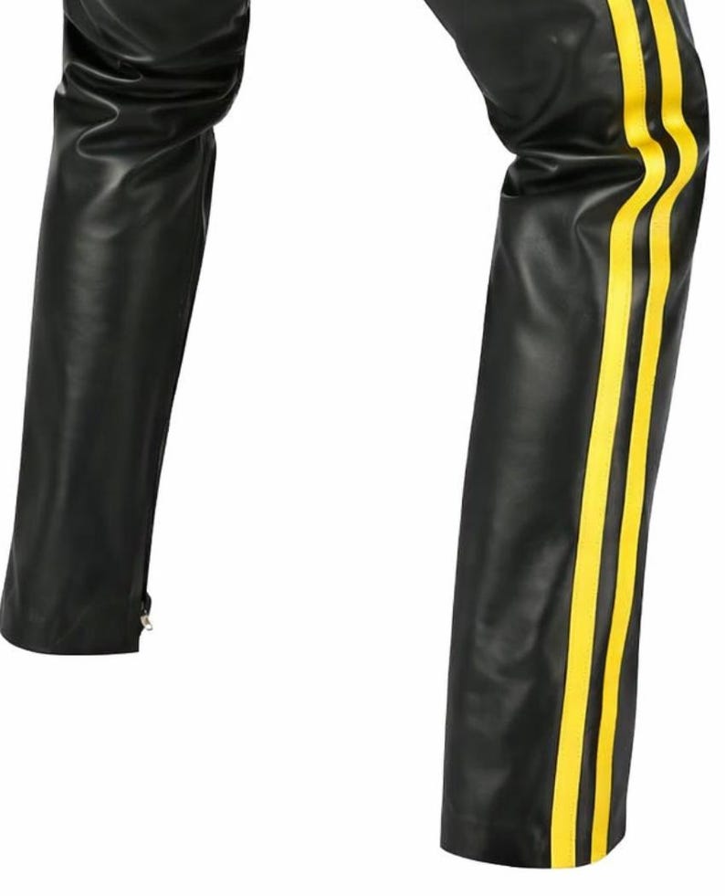 May include: Black leather pants with three vertical yellow stripes down the side of one leg. The pants have a straight leg cut and a zipper at the ankle. The material appears to be smooth and shiny.