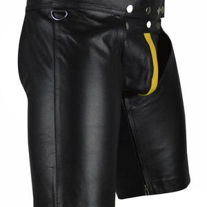 May include: Black leather shorts with a yellow stripe detail. The shorts feature a D-ring, rivets, and a zipper closure. The garment is made of smooth, shiny leather.