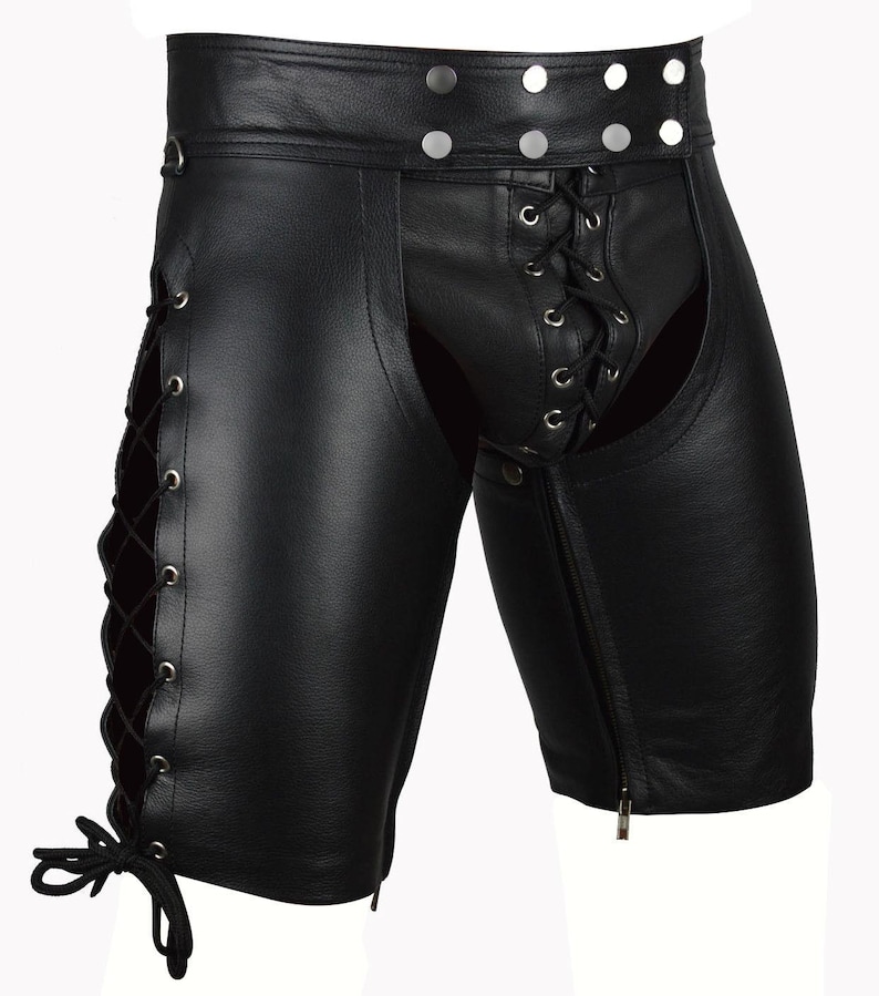 May include: Black leather chaps with a lace-up design on the sides and front. The chaps have a zipper closure on the legs and silver-tone button details on the waistband. The chaps are designed to be worn over other clothing.