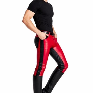 May include: A person wearing a black t-shirt, red and black leather pants, and black knee-high boots. The pants have a red front panel with a black stripe down the side. The boots are solid black.