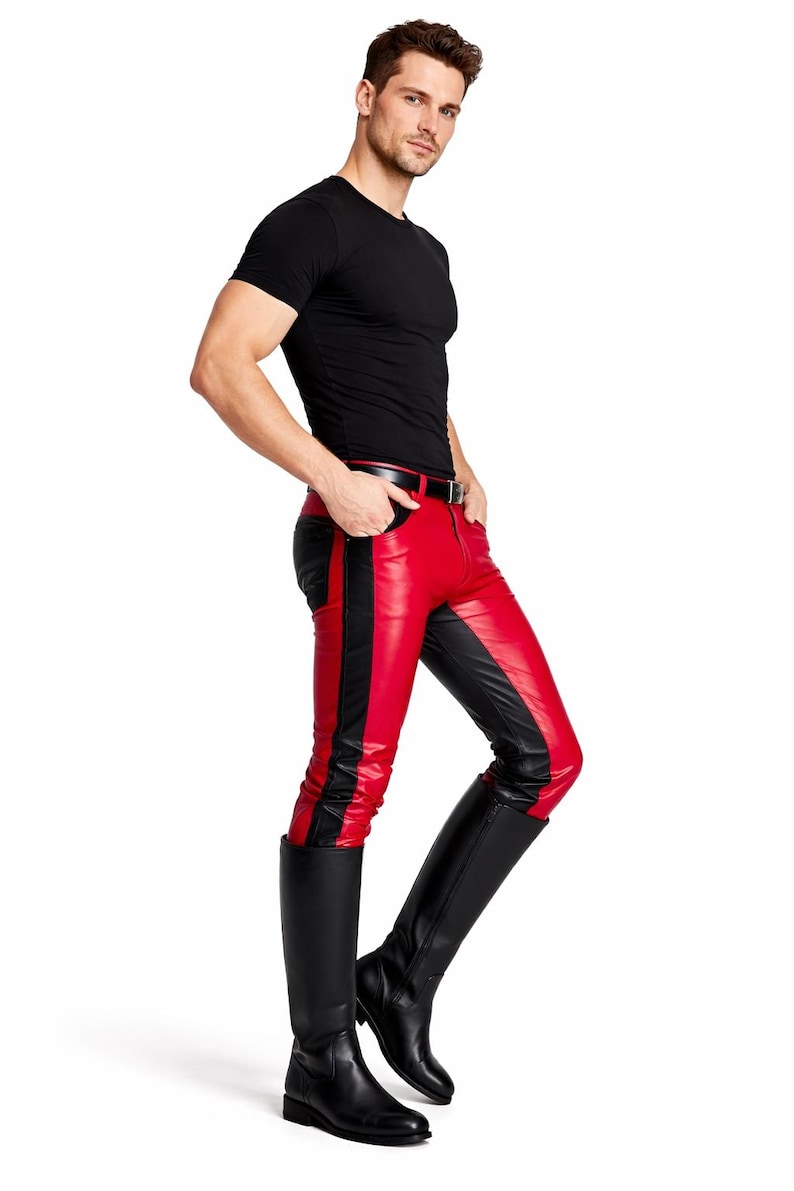 May include: A person wearing a black t-shirt, red and black leather pants, and black knee-high boots. The pants have a red front panel with a black stripe down the side. The boots are solid black.