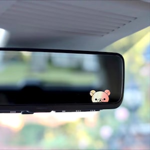 May include: A rearview mirror with a small, pink and yellow bear sticker on the bottom right corner.