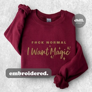 May include: Burgundy sweatshirt with gold embroidered text that reads "F*CK NORMAL I WANT MAGIC" with gold glitter stars. The text is embroidered.