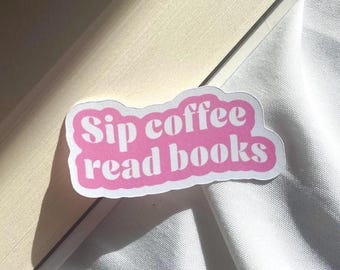 May include: A die-cut sticker with a white border and a pink background featuring the white text "Sip coffee read books" in a bold, rounded, retro-inspired font. The sticker has a smooth, matte finish and a distinct, wavy, cloud-like shape.