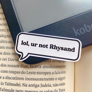 May include: A white sticker with black text that reads "lol, ur not Rhysand" in a speech bubble shape. The sticker is placed on a black e-reader.
