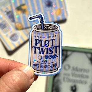 May include: A holographic sticker shaped like a soda can with blue and tan vertical stripes. The text reads PLOT TWIST pop, SINCE 1994, and EXPECT THE UNEXPECTED. A blue straw protrudes from the top of the can, which features a metallic finish.